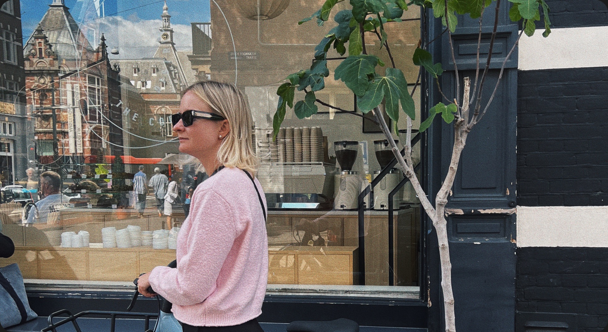 Anna Podvoiska in a pink sweater outside a café window in Amsterdam